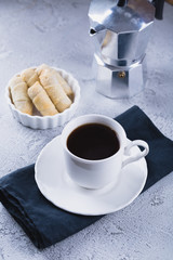 White cup of coffee with oatmeal cookies and coffee maker, breakfast concept, selective focus