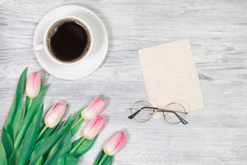 Woman working desk with coffee mug, notebook and spring tulip flowers top view in flat lay style