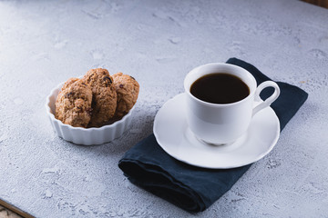 White cup of coffee with oatmeal cookies and coffee maker, breakfast concept, selective focus