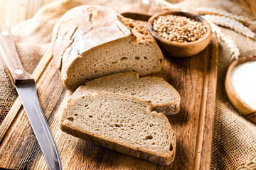 Rustic crusty loaves of bread on jute chalkboard background. Bakery concept with cut sliced homemade bread