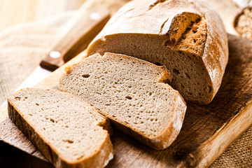 Rustic crusty loaves of bread on jute chalkboard background. Bakery concept with cut sliced homemade bread
