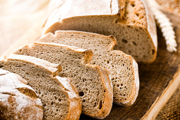 Rustic crusty loaves of bread on jute chalkboard background. Bakery concept with cut sliced homemade bread
