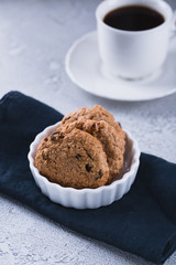 White cup of coffee with oatmeal cookies and coffee maker, breakfast concept, selective focus
