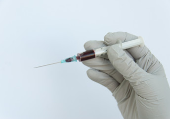 Doctor hand in white gloves holds a disposable sterile syringe filled with blood on a white...