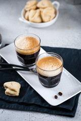 Two cups of fresh espresso on white rectangular tray with milk jar and coffee maker, copy space, breakfast concept 