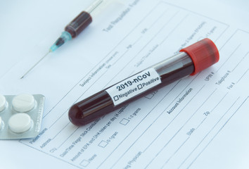 Medical form of a coronavirus test, a syringe with blood, and pills on a white background in the hospital. Close up