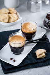 Two cups of fresh espresso on white rectangular tray with milk jar and coffee maker, copy space, breakfast concept 