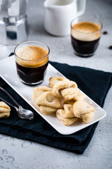 Almond cookies with a cup of fresh espresso on white rectangular tray with milk jar and coffee maker, copy space, breakfast concept 