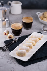 Sweet rolls with jam filling with two cups of fresh espresso with milk jar and coffee maker, copy space, breakfast concept 