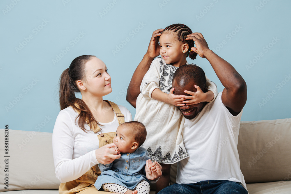 Wall mural Family posing for a photo, daughter misbehaves, having fun.