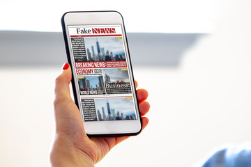 A female holding a smart phone reading fake news