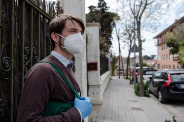 Fototapeta na wymiar White male walking on the street of a residential area with gloves and mask for shooping