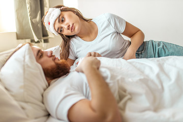 young caucasian wife wait when her husband wakes up, lie on bed. married couple at home in the morning