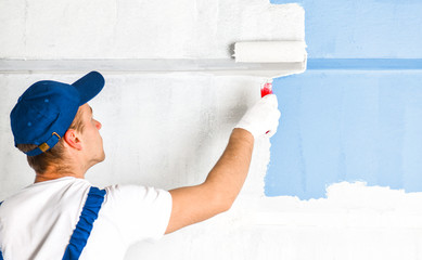 Man painting wall with roller.