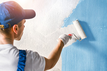 Painter painting a wall with paint roller.