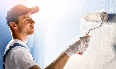 Painter painting a wall with paint roller. - obrazy, fototapety, plakaty