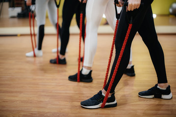 A group of young girls is engaged in fitness with an expander under the guidance of an experienced coach. Fitness, healthy lifestyle..