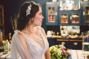 Naklejka premium Bride in beautiful dress standing indoors interior at home. Trendy wedding style shot. Wedding makeup and hairstyle. Beautiful Bride in the morning. Emotional bride in her wedding day