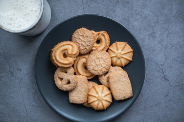 Homemade shortbread on a grey plate and a mug with milk on concrete background. Top view.