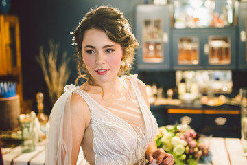 Naklejka premium Bride in beautiful dress standing indoors interior at home. Trendy wedding style shot. Wedding makeup and hairstyle. Beautiful Bride in the morning. Emotional bride in her wedding day