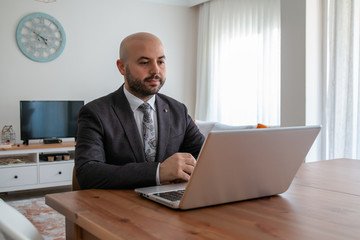 Confident businessman with beard in suit doing job interview with leptop at home.
