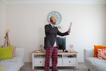young bearded man with sweatpants on top of a suit, talking to his delighted friends listening to music at home at the talet.