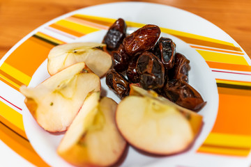 Closeup of raw vegan healthy snack or ingredients with dried medjool dates and sliced apples on plate macro