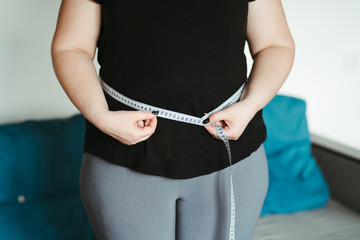 weight loss, overweight, plus size, diet. fat woman measures her waist with measuring tape