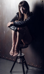 Fototapeta na wymiar Girl bodybuilder in a black leather jacket closeup posing in a photo studio. A girl showing a trained body shape. Low key style photo.
