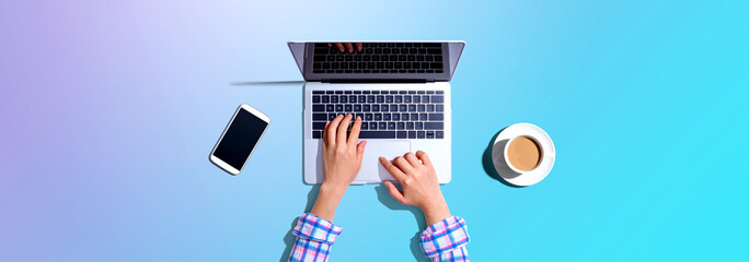 Woman using a laptop computer with a phone and a cup of coffee