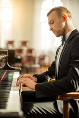 young handsome caucasian man in formal elegant suit gracefully play piano. professional pianist perform classic music