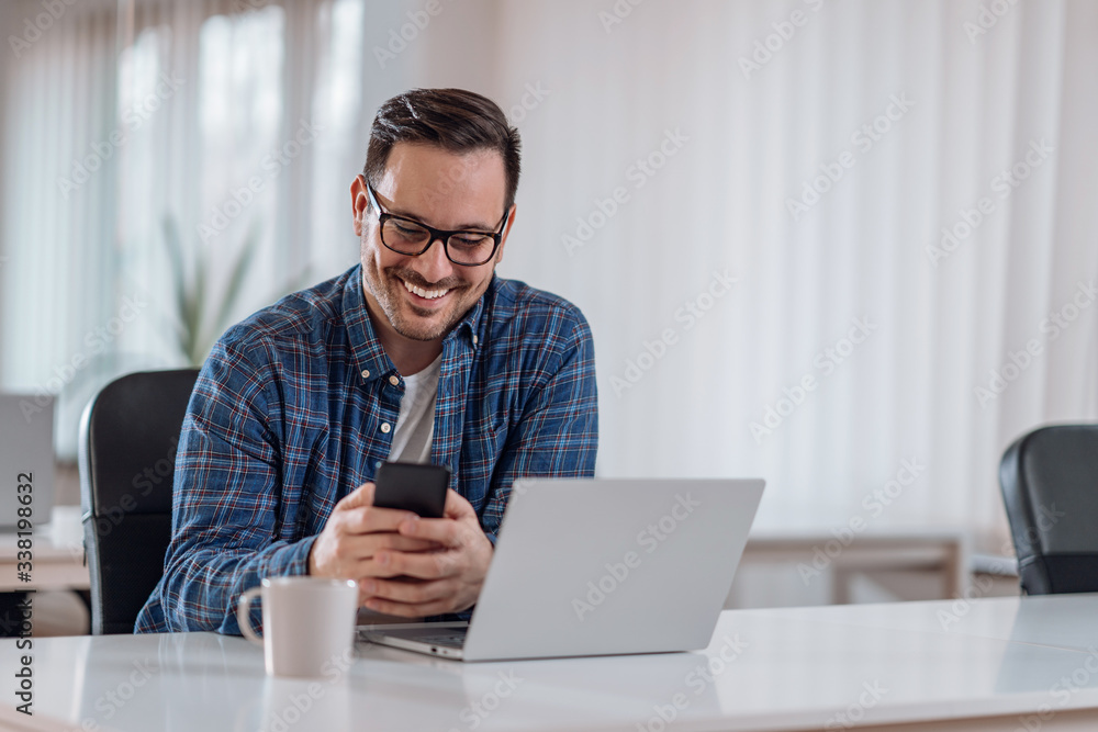 Wall mural businessman sitting at the desk and using smart phone