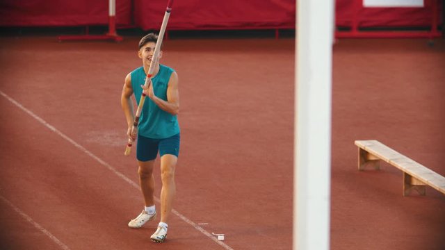 Pole vault training on the stadium - a young smiling man preparing before the jump
