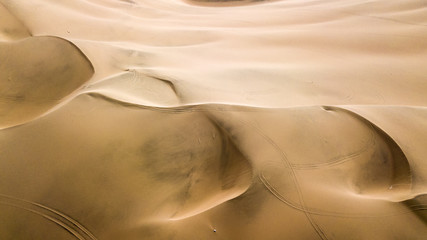 Fototapeta na wymiar Aerial top-down view of sand dunes. Sand dunes create abstract shapes during the day light. Wind formations.