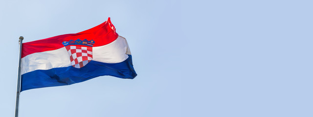 Flag of the Republic of Croatia waving in the wind on flagpole against the sky on sunny day, banner, close-up