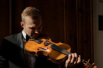 handsome caucasian guy in elegant suit practice playing violin, man with classic instrument perform...