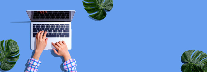 Person using a laptop computer with tropical leaves from above