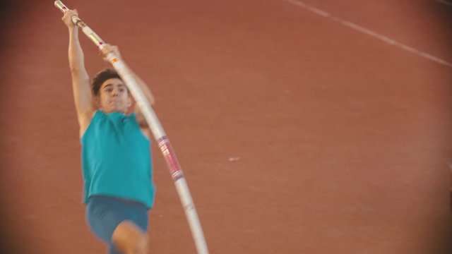 Pole vault training on the stadium - a young man running up and fails his jump