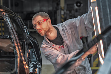 Fototapeta na wymiar An employee of the car body painting shop checks the quality