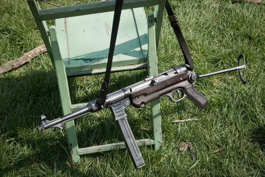 German WWII MP-40 9mm sub-mahine gun (pistol) slung over a wooden green folding chair.