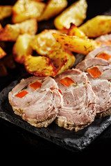 Close-up of grilled pork meat with fried potato. Black background