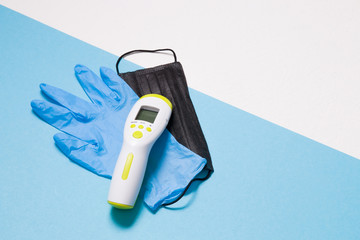 blue disposable medical glove, black face mask, infrared thermometer for non-contact temperature...