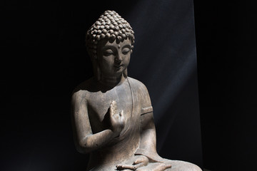 Home Buddha statue into sun light on black background calm down meditation yoga soul healing spiritual concept 