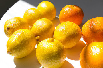 Bright yellow lemon and orange on white table under sun light 