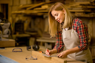 portrait of professional woodworker making marks on wooden piece, woman make handmade furniture in workshop, enjoy working alone