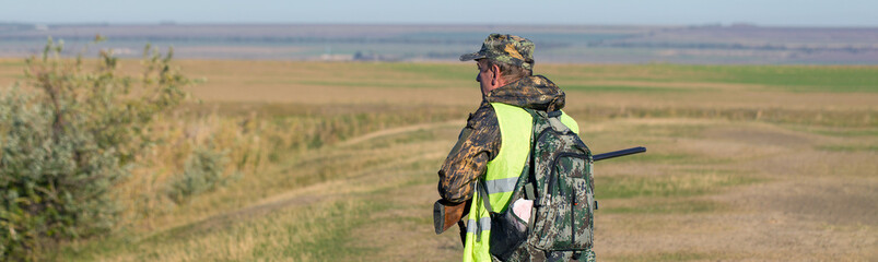 Hunter with a gun and a dog go on the first snow in the steppe, Hunting pheasant in a reflective...