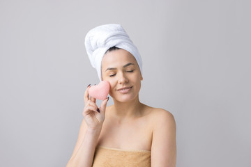 Beauty portrait of woman in white towel on head with a sponge for a body in view of a pink heart. Skincare cleansing eco organic cosmetic spa relax concept.