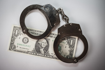 handcuffs sitting on top of US paper currency