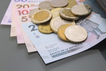 Colombia Money, Currency of Colombia, Pesos, various bills and coins inside a wallet, close-up on dark background. Cash money