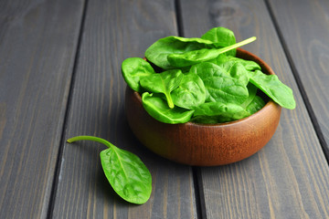 Spinach leaves in wooden bowl on dark wooden table background. Healthy vegan food trend. Vegan lifestyle concept.